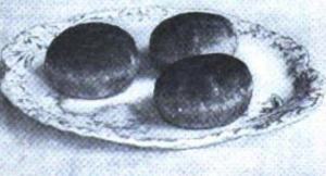 Black and white photo of three individual cakes arranged on a plate.