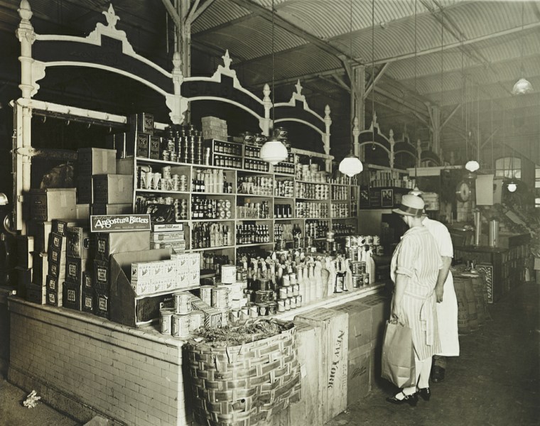 Customers shopping for canned goods at a grocery in the early 1920s