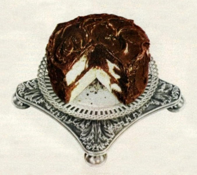 Photo of a chocolate-iced marble cake on an ornate silver serving stand.