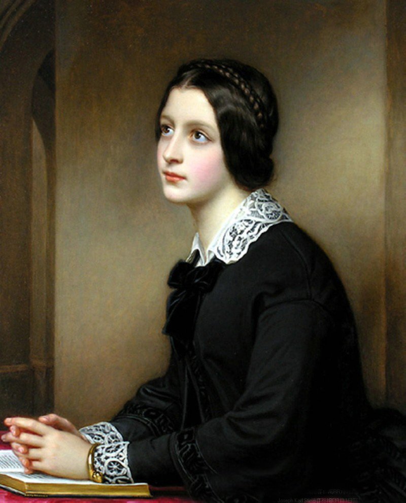 Young woman dressed in black with white lace collar and cuffs is seated at a table. A Bible is open on the table and her hands are clasped together on top of the open Bible.
