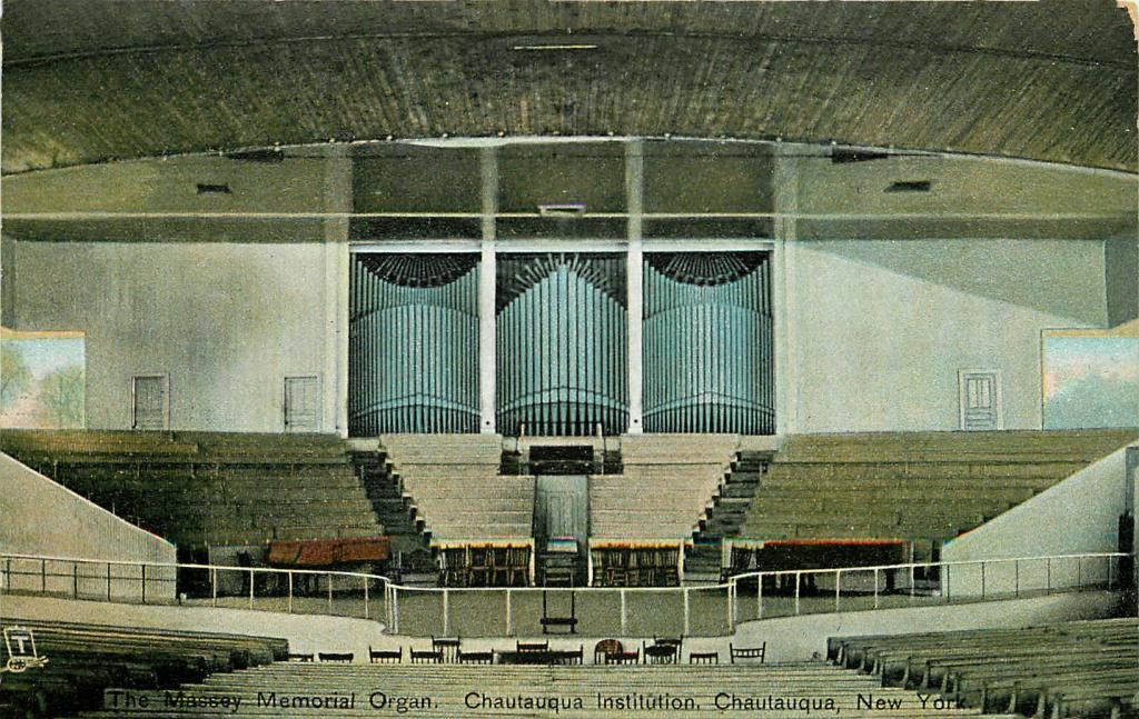 Photo of the amphitheatre stage. In the middle is an elevated platform for the organist and three large banks of organ pipes.