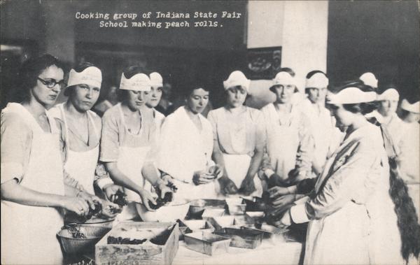 Photo of about a dozen young women gathered around a table where they are preparing peaches to make into peach rolls.