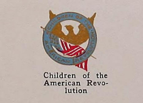Illustration a round lapel pin, which features the name of the organization in gold against a blue background. Behind the name of the club is the silhouette in gold of an eagle with its wings extended, and an American flag.