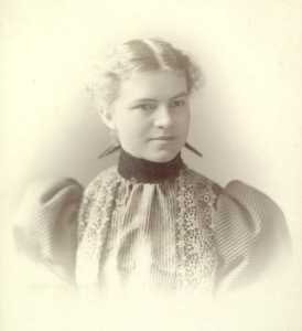 Portrait of a young woman wearing clothing with a high collar neckline and large puffed sleeves that were in style about 1890.