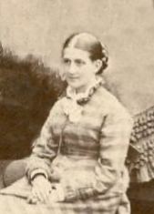 Black and white photo of Isabella wearing her hair parted in the middle and drawn smoothly back into a braided bun at the back of her head.
