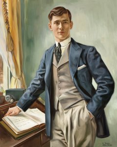 Illustration of a young man dressed in the clothes worn about the year 1910. He is standing at a desk near a window. He has one hand in his trouser pocket; with his other hand  he holds a book open on the top of the desk. 